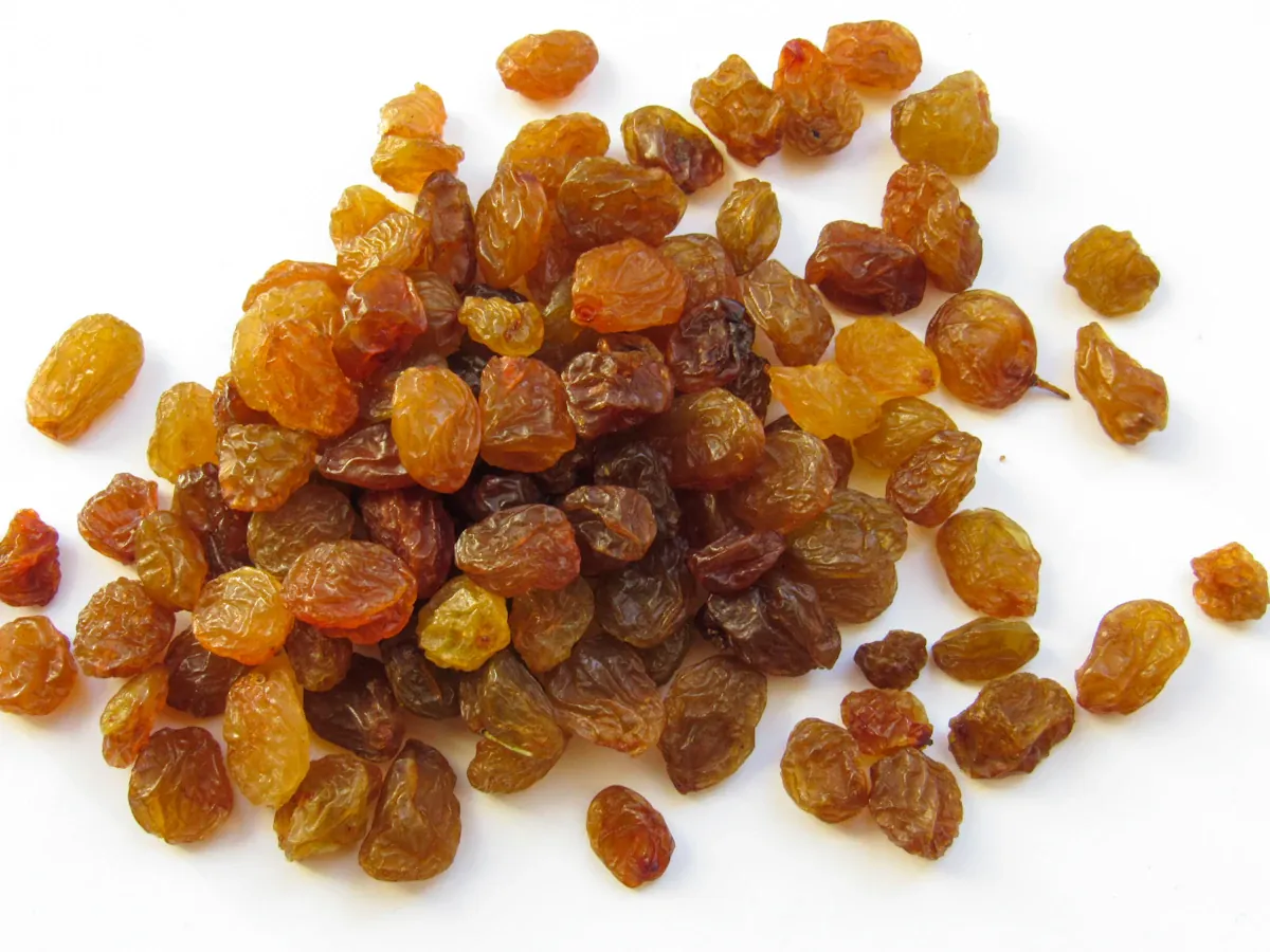 A handful of golden and brown raisins on a white surface
